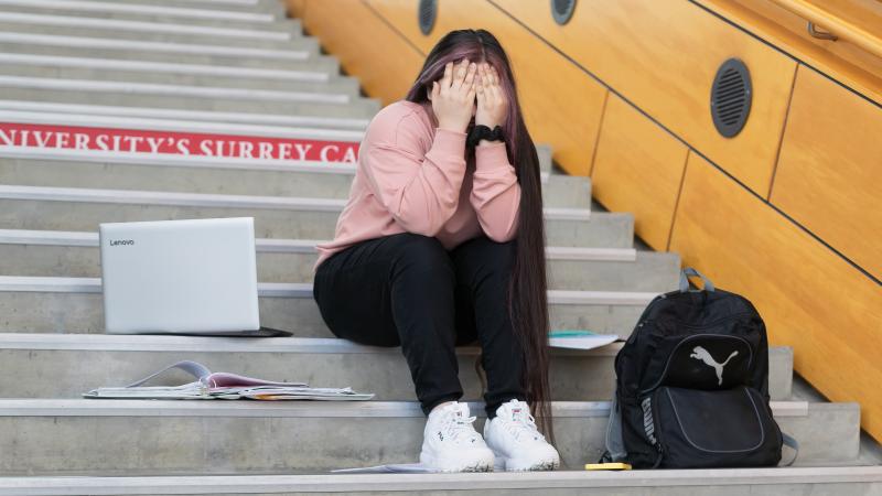 Youth stressed about university. Sitting with laptop and books. 