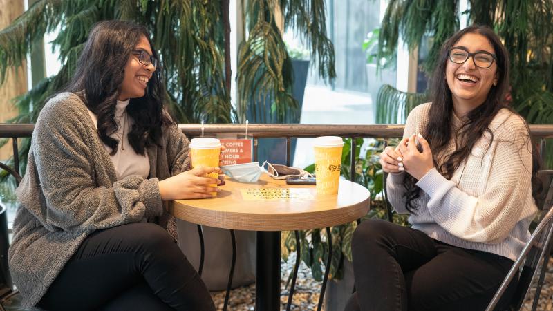 two females laughing and enjoying coffee together